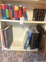 Photo of bookshelf showing colorful Harry Potter book spines on top left shelf, Lord of The Rings boxed set to right, and several large coffee table books on lower shelf including Monet and Canadian medals books.