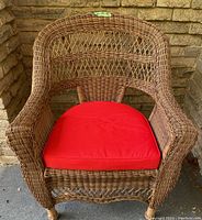Front view of the wicker style coated wire chair with red cushion showing detailed weaving and cushion.