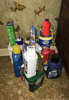 Photo showing entire group of cleaning products stacked on floor with a wall behind featuring butterfly decorations.