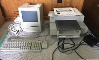 Overview of Macintosh Classic, keyboard, mouse, printer, cables and joystick on carpet