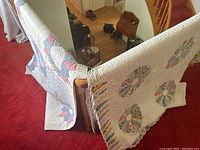 Both quilts draped over banister, showing overall patterns