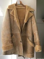 Front view of the tan sheepskin coat showing suede exterior and wool trim on collar and cuffs.