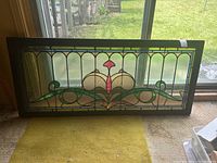 Full front view of colorful stained glass window panel leaning against background window