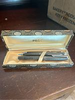 Two writing instruments in open hinged box with gold-tone silk lining and PILOT logo