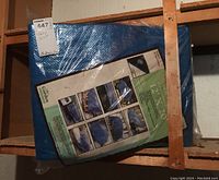 Blue polyethylene tarp in original packaging displaying product label with specifications and use cases.