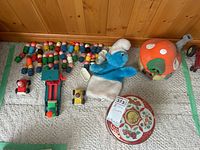 Full lot overview showing Little People figures, Smurf plush puppet, mushroom cottage plush, decorative tin