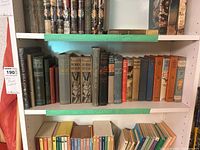 Photo showing multiple vintage hardcover books on a white shelf, including Robin Hood editions with illustrated spines and other assorted titles.
