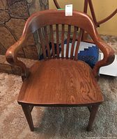 Front view of the vintage wood office chair showing curved arms, slatted back, and wood seat.