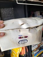 Closed white cardboard box with Danbel Brite Lite logo, showing wear and dents