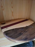 Photo showing the wooden cutting board from an angle highlighting its multi-wood sections and thumb hole.