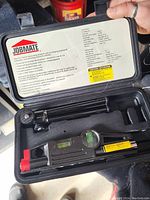 Open case showing the tool kit with spirit level, screwdriver handle, metal extension bar, and screwdriver bit inside foam padding.