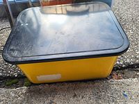 Closed yellow metal box with black lid showing overall exterior condition and color.