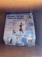 Photo of unopened sealed package showing Sexy Woman shower curtain with silhouette design and measurement details.
