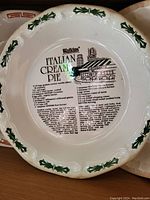 Top side of ceramic cake plate showing the recipe for Italian Cream Pie and Watkins branding with a bakery storefront illustration.