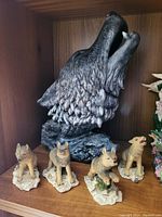 Photo showing one large black wolf head figurine and four smaller wolf figurines on textured bases.