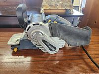 Side angle showing the sanding belt, dust collection bag, and handle of the Chicago Electric belt sander.