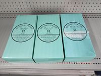 Three boxed sets of erasable ceramic place tiles called Place Tiles, each box containing 6 tiles with a dry erase marker, in teal packaging.