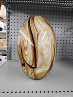 Front view of the oval glass vase showing intricate brown and cream swirls.