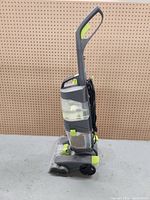 Side view of upright Hoover rug shampooer showing clear water tanks and handle.