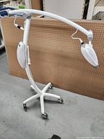 Full view of Philips Zoom teeth whitening lamp on wheeled base with two adjustable lamp heads and arm.