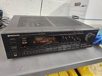 Front angle view showing the Pioneer VSX-3700S receiver powering on with tuner screen display showing 87.50 MHz frequency.