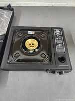 Top view showing central brass burner in square casing with control panel on the right side.