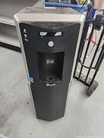 Front view of the black Quench water cooler showing water dispensing area and power button.
