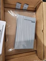 Valcom V-9964 Stacking Feedback Eliminator device inside original cardboard packaging in plastic wrap.