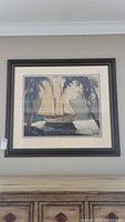 Full view of framed sailboat painting hanging on wall, shows entire artwork and frame