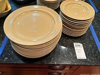 Photo showing stacks of beige ceramic plates and saucers with the concentric circle design on a countertop.