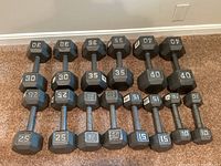 All seven pairs of dumbbells arranged on carpet