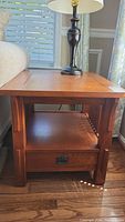 Full view of the Bassett end table showing wood finish, drawer, and open lower shelf.