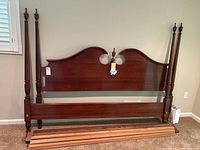 Full view of the bed frame assembled showing the headboard with double-arched top, footboard, side rails, and slats arranged in front.