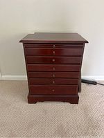 Front view of the wooden jewelry box showing six drawers with brass keyhole locks.