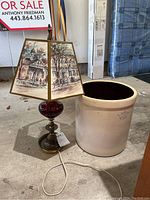 Photo showing the table lamp with painted scenic shade next to the large ceramic crock on a concrete floor