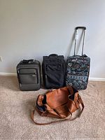View of all four luggage items together showing leather duffel and three roller bags
