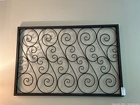 Full front view of large rectangular metal wall art with decorative scroll design.