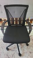 Front view of black mesh office chair showing the cushioned seat and mesh backrest.