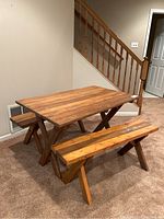Overall view of picnic table with two benches set indoors on carpeted floor, showing wood slat construction and stained finish.