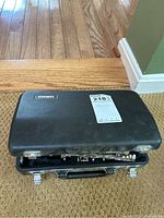 External view of black hard case with Yamaha label and auction sticker, case partially open with clarinet sections visible inside.