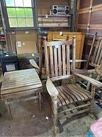 Two wooden rocking chairs and a wooden side table shown in a garage setting with visible wear and scratches on the surfaces.