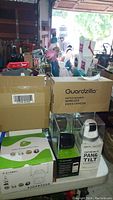 Boxes of Guardzilla wireless video cameras and sensor light smartcam on a table, some items partially visible.