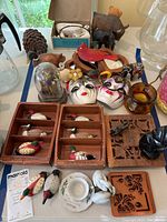 Overview of lot showing Enesco duck figurines, Mardi Gras masks, animal figurines, dollhouse bathroom set, John Wayne figure and other small collectibles