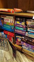 Shelf view showing Operation, Raceways, Twister Moves, Guesstures, Yahtzee and other boxed games and puzzles