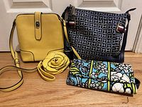 Four items in the lot including Vera Bradley wallet with floral fabric, Tommy Hilfiger navy monogram shoulder bag, yellow shoulder bag, and yellow flower coin purse.