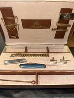 Full view of jewelry collection in vintage box showing bracelet, pocket knife, cufflinks, stick pin, and tie clips.