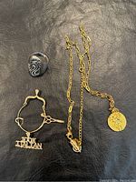 Photo showing the silver ring with abstract design, the 14k gold charm bracelet with '100% Italian' and scissors charms, and the 14k gold chain with a round textured pendant