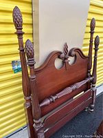 Full view of the vintage mahogany twin bed frame showing four poster bed with detailed pineapple finials on each post, headboard with carved top rail and footboard with matching wood tone.