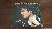 Front cover of the vinyl single showing Michael Jackson holding a microphone in a close-up photo against a dark background with text 'Another Part of Me Michael Jackson' at the top.