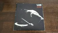 Front of U2 Desire 45rpm vinyl record sleeve with black and white drummer image and U2 logo.